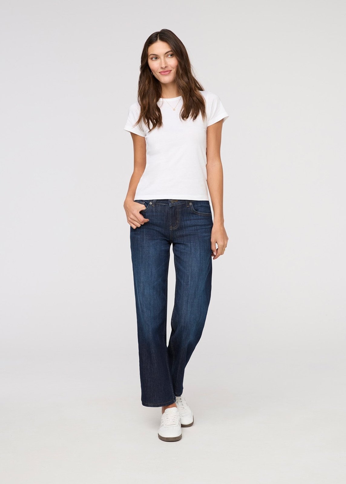 Woman wearing a white t-shirt and blue jeans on a white background