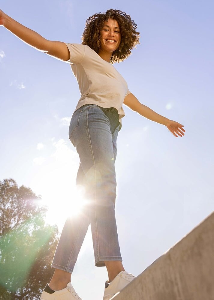womens light blue mid rise relaxed stretch jeans outside in the sun